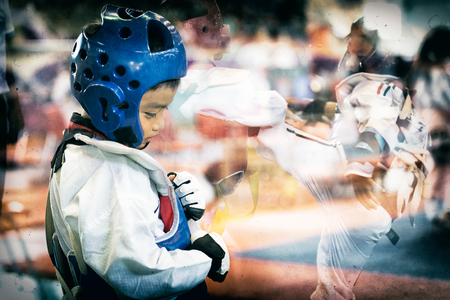 Taekwondo Asian kid with head guard. Double exposure another player during the tournament taekwondo kids in stadiums. Add old film filter and dust for feeling of former athlete history.の写真素材
