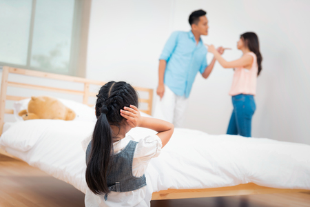 Family problem and child with background at quarrel of parents. Sad little girl is unhappy while in the bed room and cry against arguing parents at home or Conflict happened in the familyの写真素材