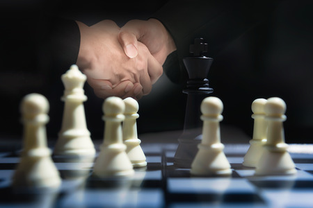 Double exposure check hand of businessman with Chess game on board. Management with partnership for Trading and Overcome the Fear of Confrontation.の写真素材