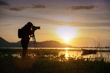 Travel photographer taking a photo with nature the lake in sunset to nightlife with camera on tripod, Focusing attention nature mountain view and lake,  Natural photography relaxing concept.の写真素材