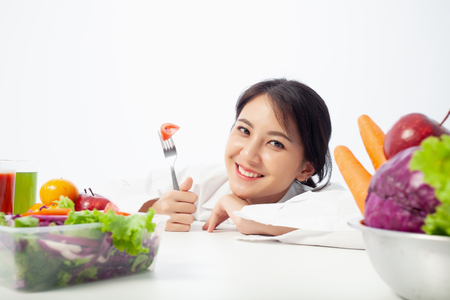 Asian young woman is happy holding a fork in hand with vegetables,  Healthy, Fresh food, Clean eating recipes to fuel body from the inside out concept.の写真素材