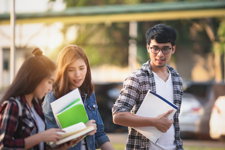 Three Asian people, Scholarship Students walking with smile in park and discussing about latest content of textbook in park at university after learning in classroom. Life of studying and friendship conceptの写真素材