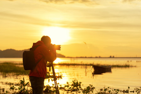 Travel photographer taking nature the lake in sunset with camera on tripod.の写真素材