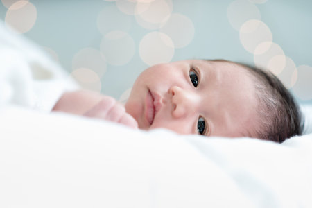 Newborn portrait on the white blanket in doubts faces with bokeh background. Selection focuses on the eye.の写真素材