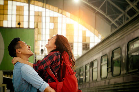Encounter of  Asian Young Couple happy hugging in love on street after arrival in summer with a warm sunlight background.の写真素材