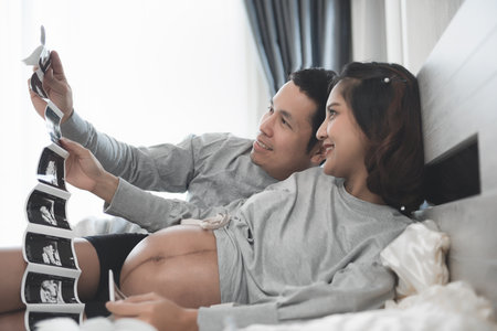 Couple happiness in love pregnant. Pregnant couple looking at an ultrasound in bed at home. Romantic...