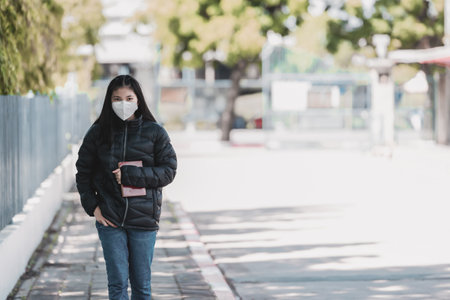 High school teenage students walking to school alone while wearing face masks as protection against infectious diseases outdoors during coronavirus pandemic. New normal life of student concept.の写真素材