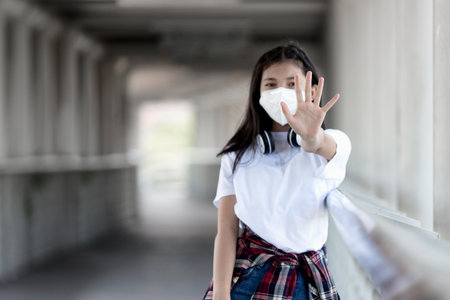 Asian Young Woman wearing protective mask against coronavirus, covid19 and stopping people to interact with each other in public place, during covid19 virus pandemic.の写真素材