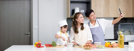 Asian family an egg into the bowl and daughter whisking eggs in bowl on white table and looking...