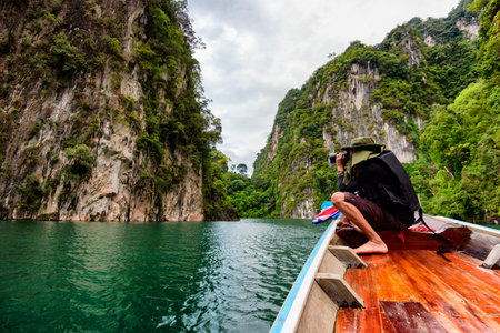 Man traveler photograph relaxing and floating in a boat on the asia lake or among the islands with mountains in backgroundのeditorial素材