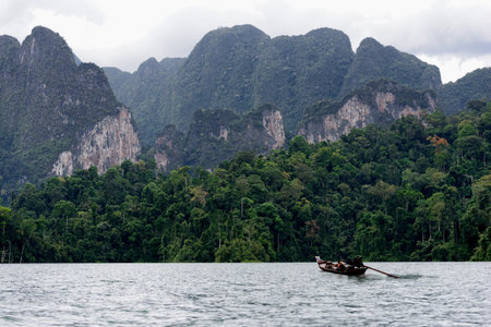 Long-tailed boat floating on the asia lake in the among the islands with mountains in background at Rajjaprabha dam (Chiewlarn dam) at Surat Thani Province of Thailand.のeditorial素材
