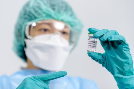 Coronavirus COVID-19 vaccine vial in female doctor hands for injection with syringe. Using prevent COVID-19, Medicine and Healthcare concept. Selection focus on vial..の写真素材