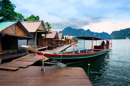 Long-tailed boat floating on the asia lake and Raft house homestay in the among the islands with...