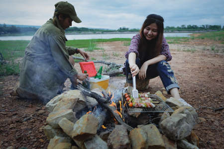 Happy friends camping enjoying bonfire in nature, Partying in camping, Asian young women people celebrating during vacation, Summertime and travel activity.の写真素材