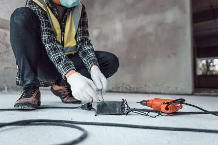 Hand connecting power outlet to an electric tool no electrical plug cause electric shock, Be unaware of worker,  Work accidents electric shock in the workplace, Selection focus shooting on his hand.の写真素材