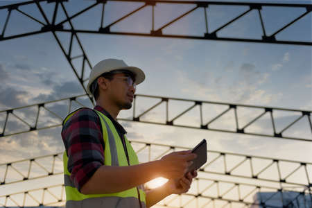 Engineering Consulting People on construction site holding tablet in his hand. Management in...