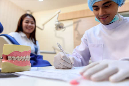 Dentist writing patient data record after treatment on desk in dentist's office