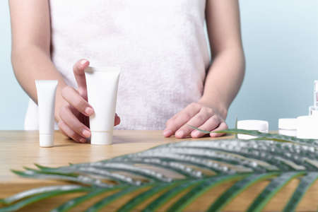 Close up hand of Young woman while pick packaging of cream product on table. Concept of safety in...
