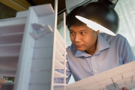 Architects worked thinking design architecture with building model, Design from his idea stationery on desk office. Startup and analysis of the architecture of building structure.の写真素材