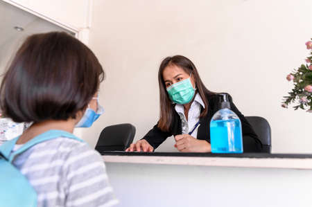 Teacher screening and records data of kindergarten students before entering the classroom for Coronavirus prevention. New social interaction as part of the transition from home to school.の写真素材