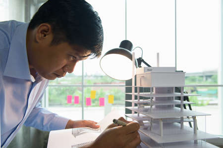 Architects worked thinking design architecture with building model, Design from his idea stationery on desk office. Startup and analysis of the architecture of building structure.の写真素材