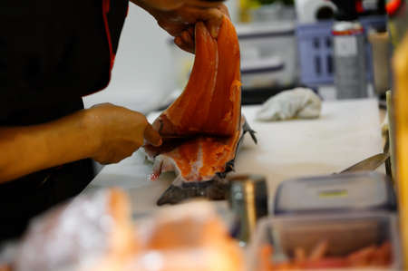 Fresh salmon fillet close-up on white cutting board table while filleting or slicing by chef in cooking room. Selection focusing on salmon fillet with Soft focusing shooting.の写真素材