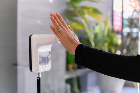 Woman raising hand at check infrared temperature measurement screening point for COVID-19 â€‹or...