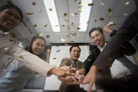 Conference room workers team meeting and wear office uniform suit everyone grin while harmony hands and one guy show donât give up all, Celebrate success and Build commitment to the employee and teamの写真素材