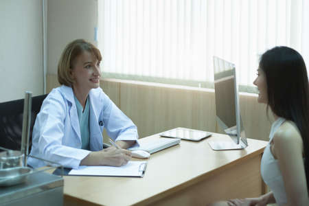 Caucasian senior woman doctor happy while gives advice to the patient in medical office on during the day of workの写真素材