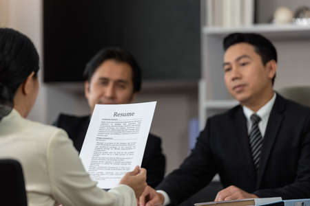 Businesswoman review requirement detail in resume for job interview in office while Employer reviewing and observe the behavior of the new applicant, Focus on head of resume paperの写真素材