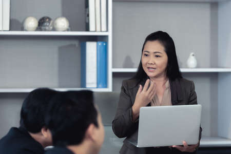Professional businesswoman or marketologist making presentation and coaching to her colleagues with laptop in office during business meetingの写真素材
