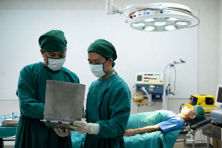 Doctors or surgeons with Physician assistant standing to discussion about a patient case in an operating room before performing difficult operations, Surgery on patient that requires knowledge.の写真素材