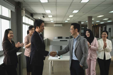 Businessman in smart office suit shaking their hands with partners and secretary team of both sides after successfully negotiated business together in the business officeの写真素材