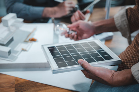 Energy engineer professionals discussion about calculating to use pure energy nature and Installing solar panels on roof house to generate electricity working with model, and Solar panel sampleの写真素材