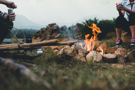 Campfire in camping of people camper group in nature near the mountains with coffee brewing equipment. Selection focus at bonfire. **Focus**の写真素材