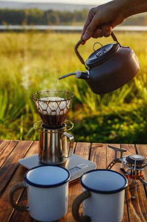 Outdoor coffee drinks on wooden table with natural mountain background and soft sunrise while coffee dripper, coffee drip with other equipment. Vertical image with copy space.の写真素材