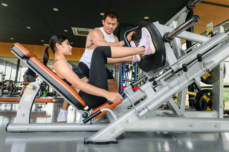 Personal trainer or Fitness Instructor helping young woman at gym
