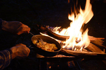 Golden Roast Potatoes with Savory Garlic Butter on a frying pan near  bonfire natural at night outdoor, Homemade Meal.の写真素材