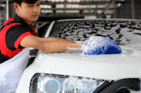 Man Worker use Soap Washing and Taking Care of Vehicle car body with Diligence, Car Washing and Detailing to Shiny and Clean Vehicles for Automotive Maintenance.の写真素材
