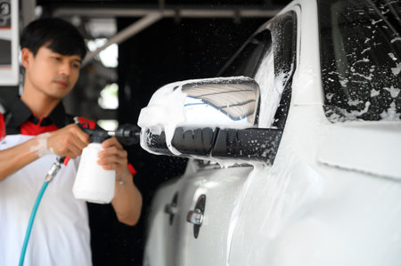 Man Worker use Foam Sprayer to Washing and Taking Care of Vehicle car body with Diligence, Car Washing and Detailing to Shiny and Clean Vehicles for Automotive Maintenance.の写真素材