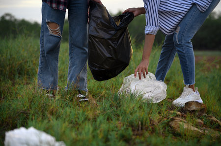 Closeup of hands with plastic garbage bags. Two female volunteers collect garbage and plastic waste...
