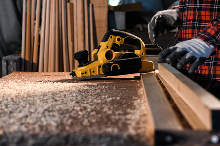 Carpenter craftsman using electric hand wood planer making pool cue or snooker cue in carpentry...