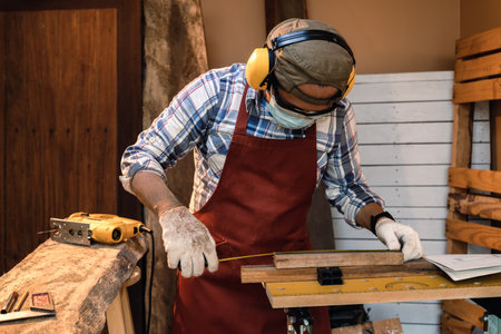 Carpenter use Measuring tape and pencil to marking on timber for cut.