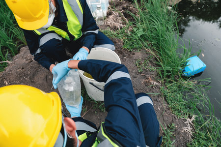 Environmental Engineers Take Water Samples Into Bottles at Rotten Smelly Pond Water Sources, May Be Contaminated by Toxic Waste or Suspicious Pollution Sites.の写真素材