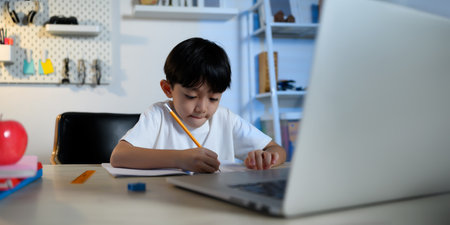 Asian Kid Boy Focused on Homework and Learning Alone in Room at Home, Serious Asian Kid Concentrating on Homework, Studying and Success, Homework and Education of Asian Kids Concept in Banner Size.の写真素材