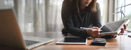 Alternative energy engineers hold solar panel samples while learning design and calculation for energy accumulation in photovoltaic panels installed. Banner size with copy space.の写真素材