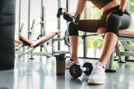 Woman fitness training an exercise class in the gym. Weight lifting or holding dumbbells for beginners. Fitness exercise building muscle, Lifestyle and health of women concept.の写真素材