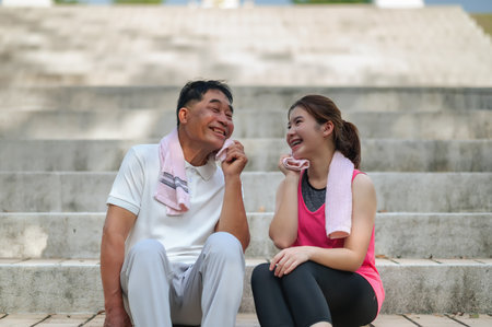 Father and daughter take a break from jogging together.の写真素材
