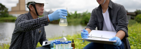 Two Environmental Engineers Inspect Water Quality and Take Water sample notes in The Field Near Farmland, Natural Water Sources maybe Contaminated by Toxic Waste or Suspicious Pollution Sites.の写真素材