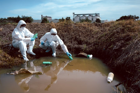Team of scientists or biologists wears protective clothing to inspect chemical-filled bottles of...